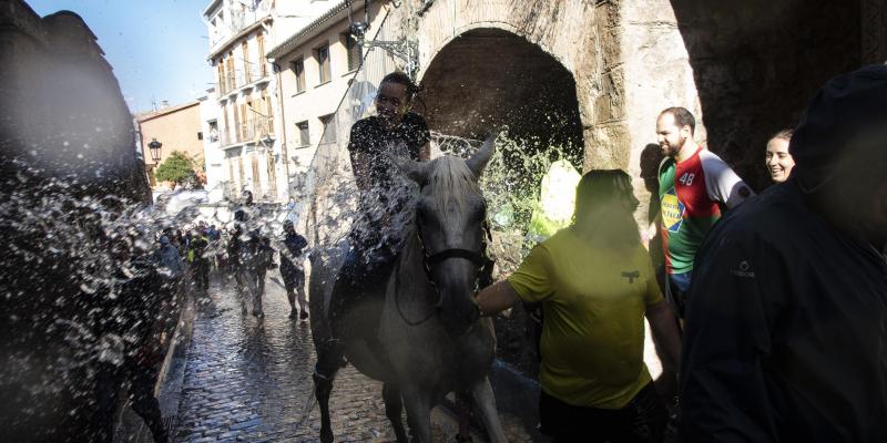 Cavalls i cavallistes remullats al seu pas pel safareig de la Pietat. FOTO: Anna E. Puig