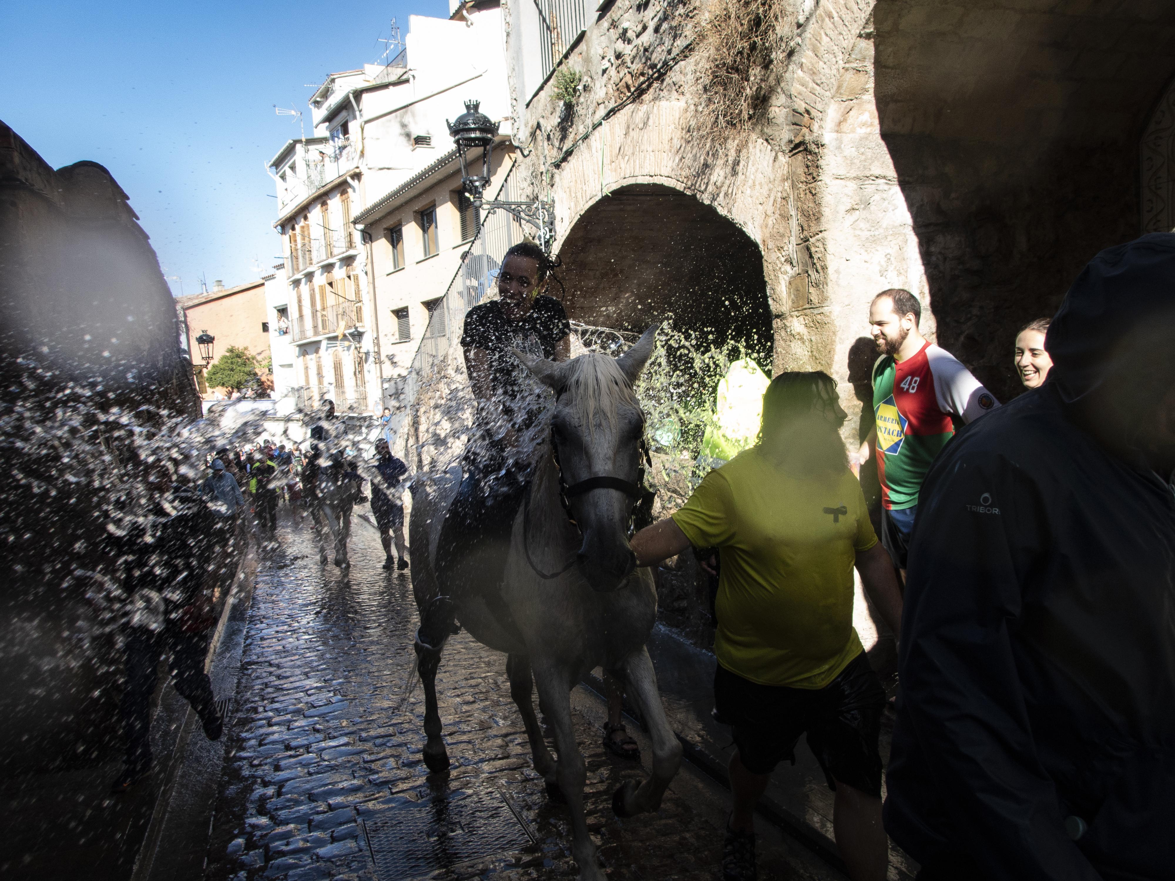 Cavalls i cavallistes remullats al seu pas pel safareig de la Pietat. FOTO: Anna E. Puig